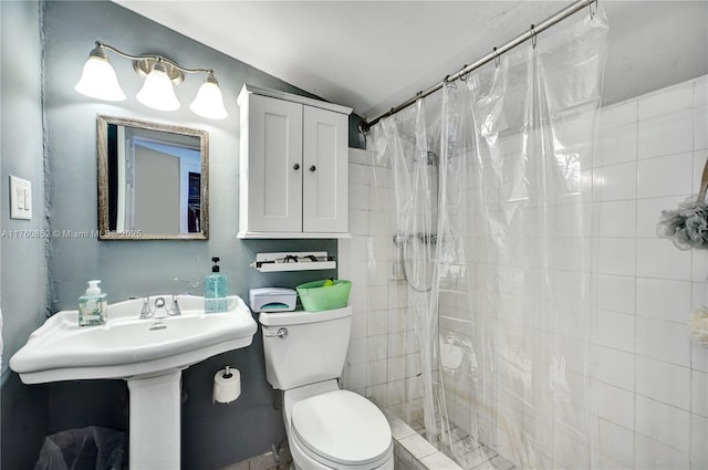 bathroom with toilet, tiled shower, and vaulted ceiling