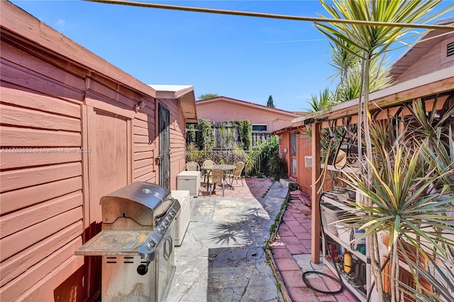 view of patio featuring outdoor dining space, a grill, and fence