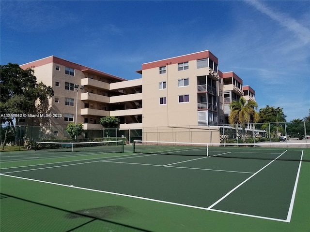 view of tennis court with community basketball court and fence