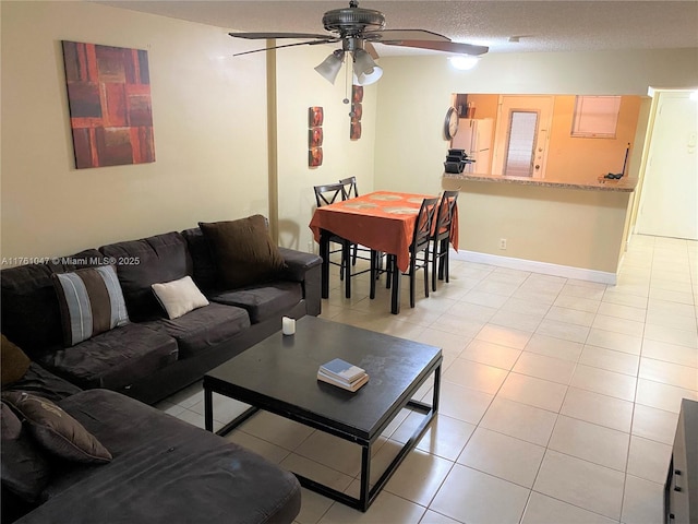 living area featuring light tile patterned floors, baseboards, a textured ceiling, and a ceiling fan