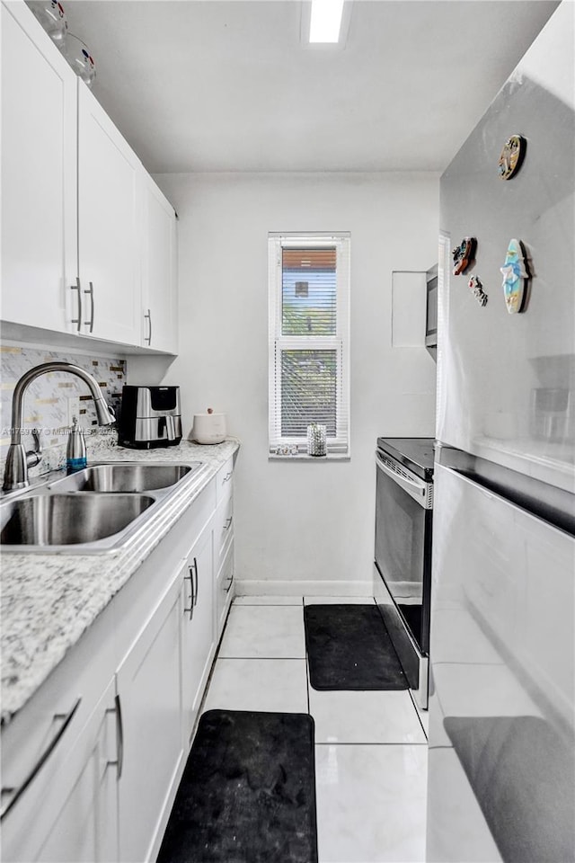 kitchen with light countertops, light tile patterned floors, appliances with stainless steel finishes, white cabinets, and a sink