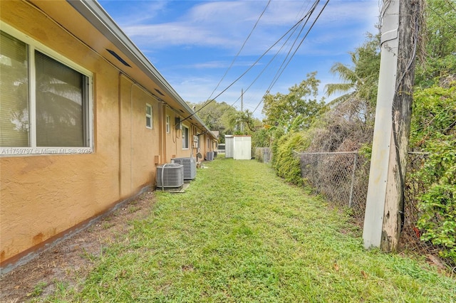 view of yard featuring central AC and fence