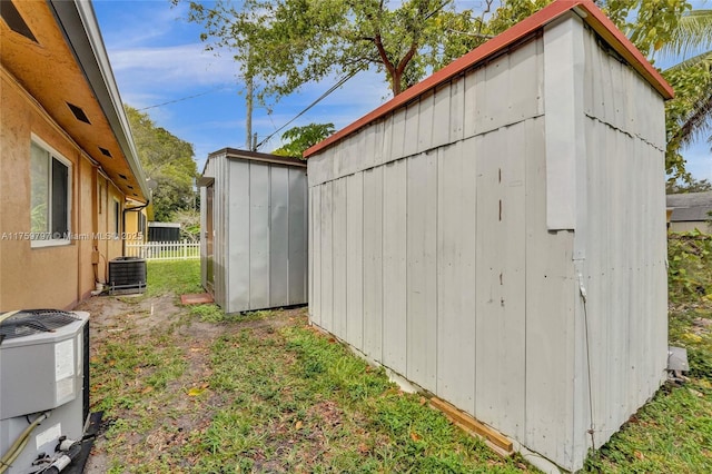 view of shed featuring central AC unit and fence