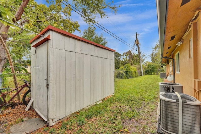 view of shed with central AC unit and fence