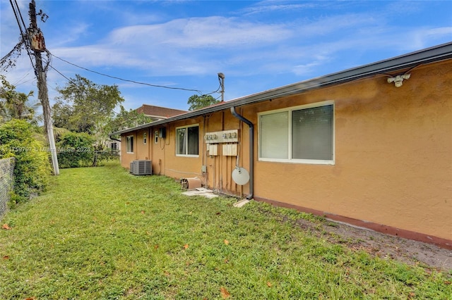 view of side of home with a yard, fence, cooling unit, and stucco siding