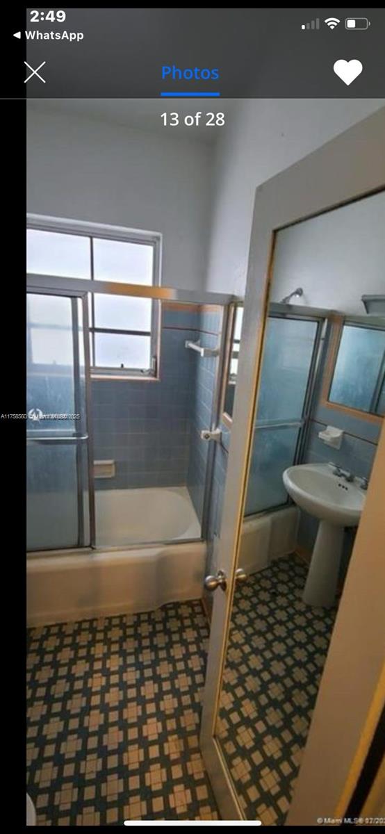 bathroom with bath / shower combo with glass door