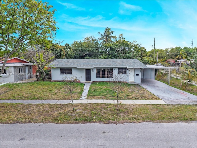 ranch-style home with a carport, a front yard, driveway, and stucco siding