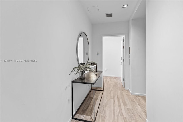 corridor with visible vents, baseboards, and light wood-style flooring