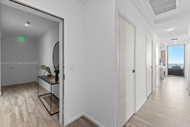 corridor with visible vents, baseboards, and light wood-style floors