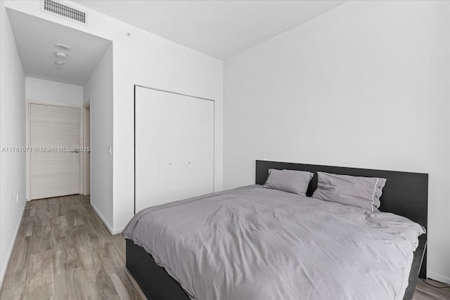 bedroom featuring a closet, visible vents, baseboards, and wood finished floors