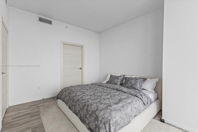 bedroom featuring visible vents, baseboards, and wood finished floors