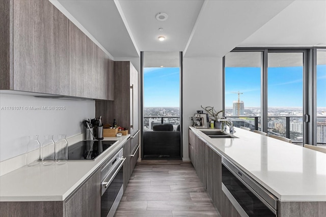 kitchen with oven, floor to ceiling windows, light countertops, modern cabinets, and a sink