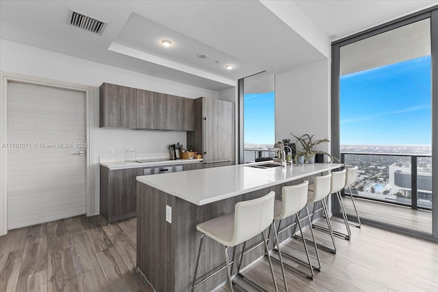 kitchen with a wall of windows, visible vents, a sink, a kitchen bar, and modern cabinets