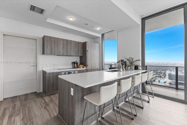 801 S Miami Ave Unit 5509, Miami, FL 33130 - kitchen featuring a breakfast bar, a wall of windows, modern cabinets, light countertops, and light wood-type flooring