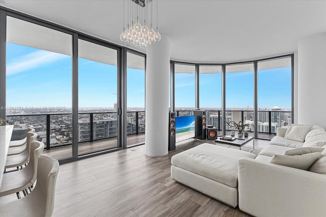 living area with expansive windows, an inviting chandelier, and wood finished floors