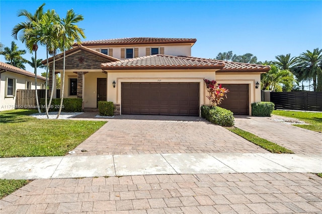 mediterranean / spanish-style house with stucco siding, decorative driveway, a garage, and fence