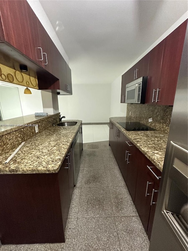 kitchen with baseboards, granite finish floor, a sink, decorative backsplash, and appliances with stainless steel finishes