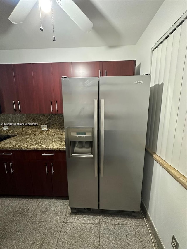 kitchen with granite finish floor, stainless steel fridge, reddish brown cabinets, and ceiling fan