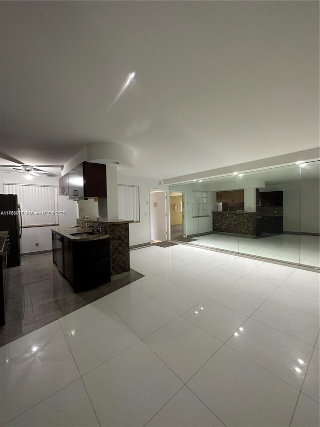 kitchen with tile patterned flooring, open floor plan, freestanding refrigerator, and a sink