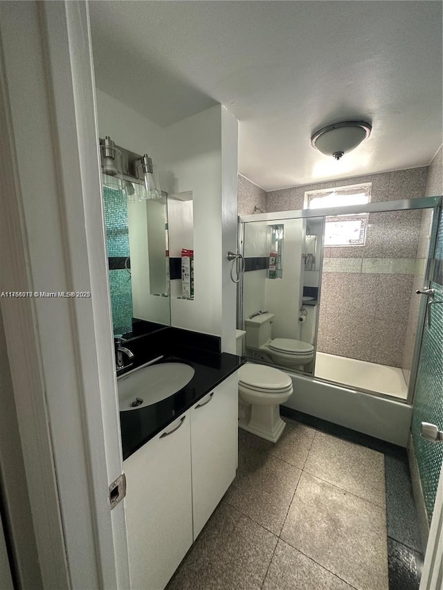 bathroom with combined bath / shower with glass door, toilet, and vanity