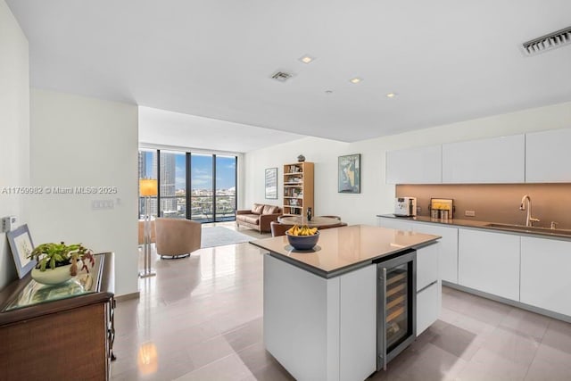 kitchen with wine cooler, visible vents, expansive windows, and a sink