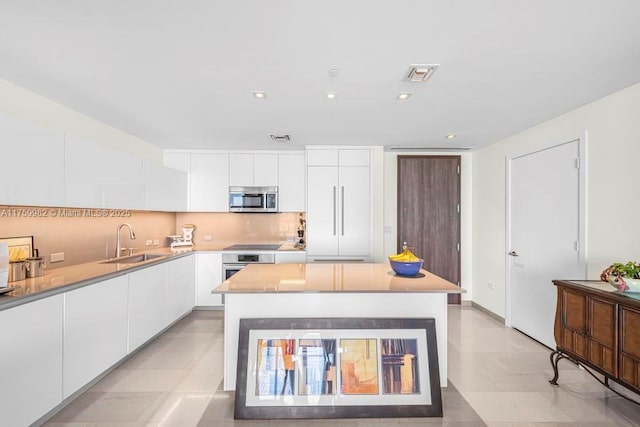 kitchen with a sink, stainless steel appliances, modern cabinets, and white cabinets
