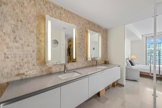 ensuite bathroom with a sink, tasteful backsplash, ensuite bath, and double vanity