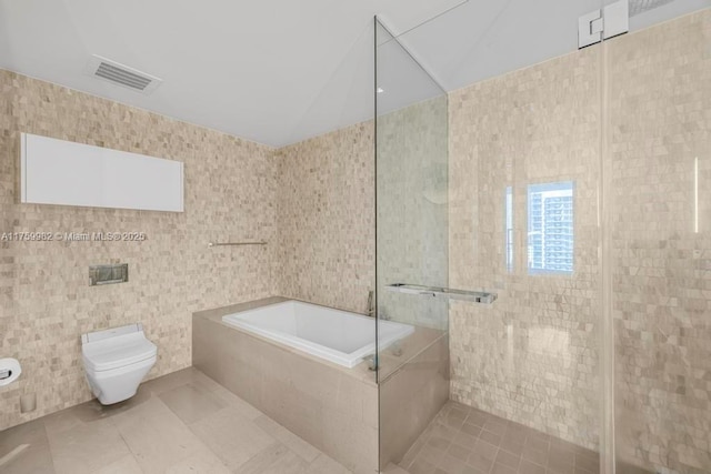 bathroom with visible vents, a garden tub, toilet, tile walls, and a shower stall