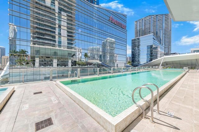 view of swimming pool with a view of city and fence