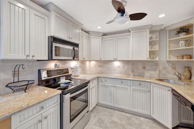 kitchen featuring a sink, open shelves, appliances with stainless steel finishes, decorative backsplash, and light stone countertops