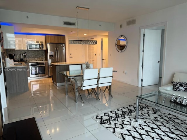 dining area featuring light tile patterned floors, visible vents, and baseboards