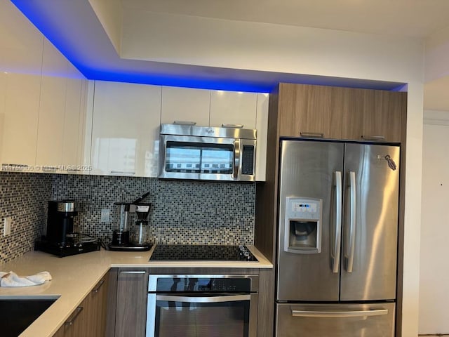 kitchen featuring brown cabinets, modern cabinets, appliances with stainless steel finishes, light countertops, and decorative backsplash