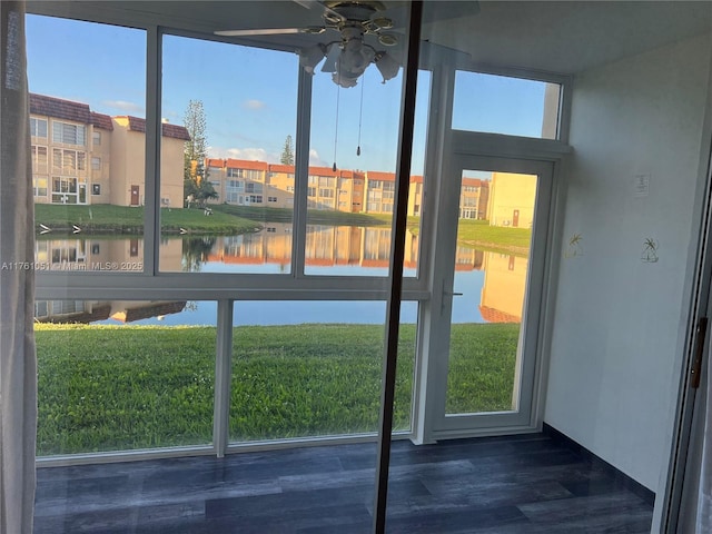 entryway with a wealth of natural light, wood finished floors, ceiling fan, and a water view