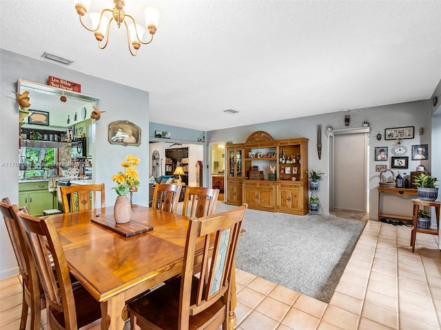 dining space featuring light tile patterned floors, visible vents, a textured ceiling, and an inviting chandelier