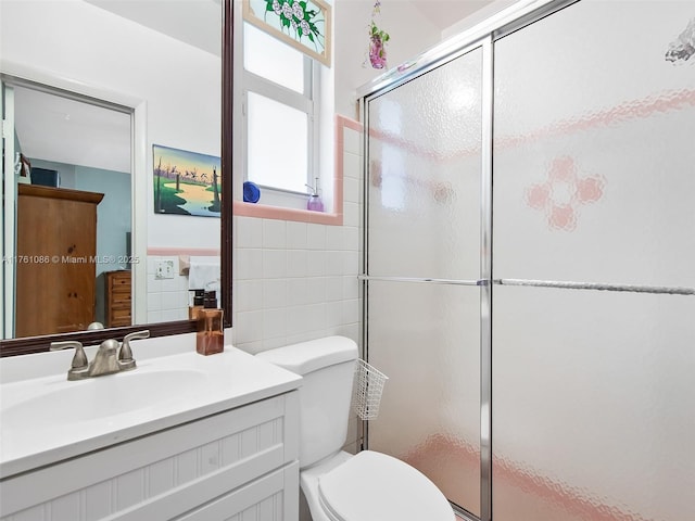 bathroom with toilet, a stall shower, tile walls, and vanity