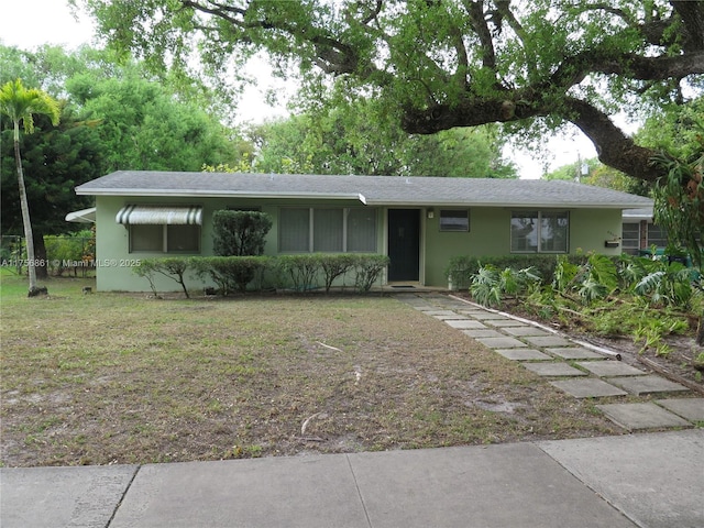 ranch-style home featuring stucco siding and a front lawn