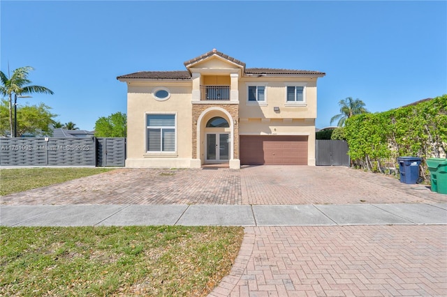 mediterranean / spanish-style house with a gate, fence, stucco siding, french doors, and decorative driveway