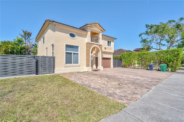 mediterranean / spanish home featuring fence, stucco siding, decorative driveway, a balcony, and an attached garage