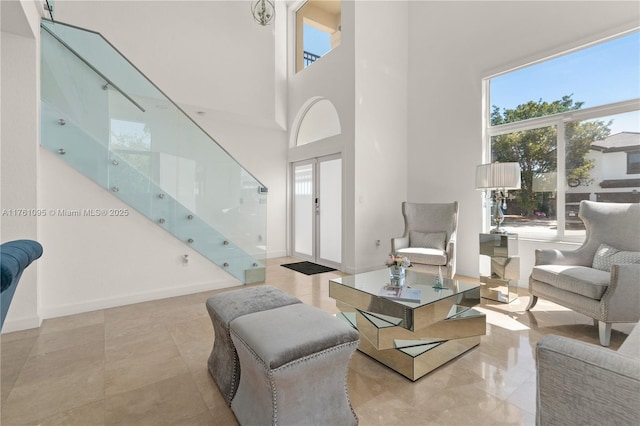 living area with baseboards and a towering ceiling