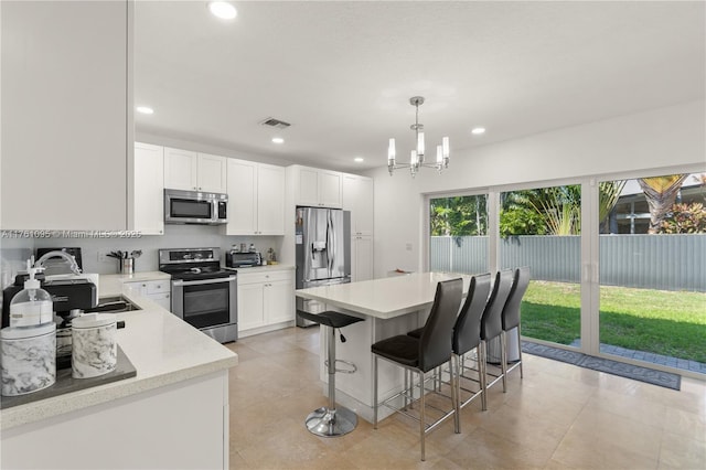 kitchen featuring a breakfast bar, light countertops, recessed lighting, appliances with stainless steel finishes, and white cabinetry