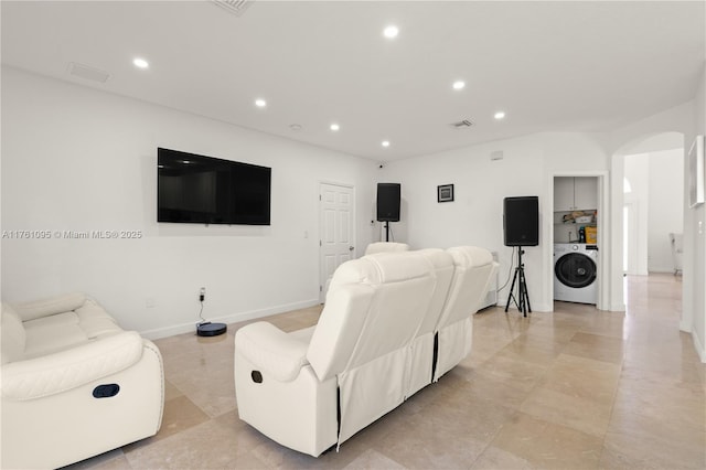 living room featuring washer / clothes dryer, recessed lighting, arched walkways, and baseboards