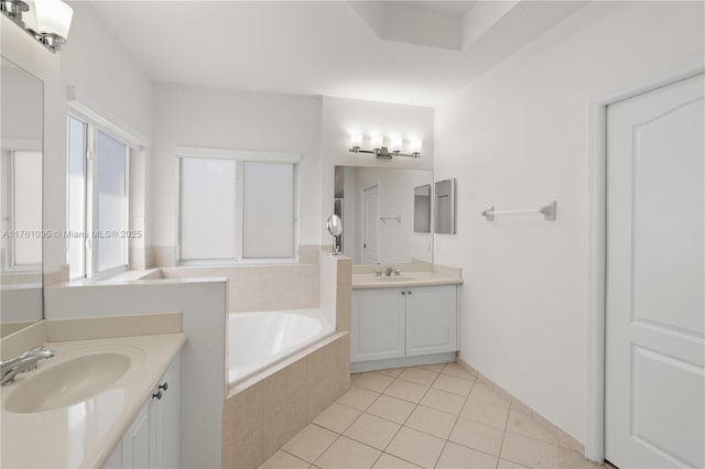 full bath featuring two vanities, tile patterned floors, a bath, and a sink