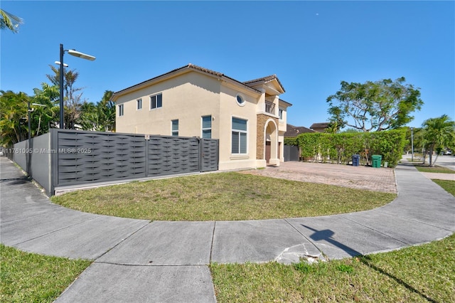 view of front of property with a front lawn, a tiled roof, fence, and stucco siding