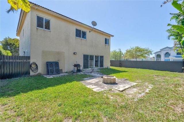 rear view of house with a yard, stucco siding, a patio, and a fenced backyard