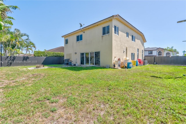 back of property featuring a yard, central air condition unit, a fenced backyard, and stucco siding