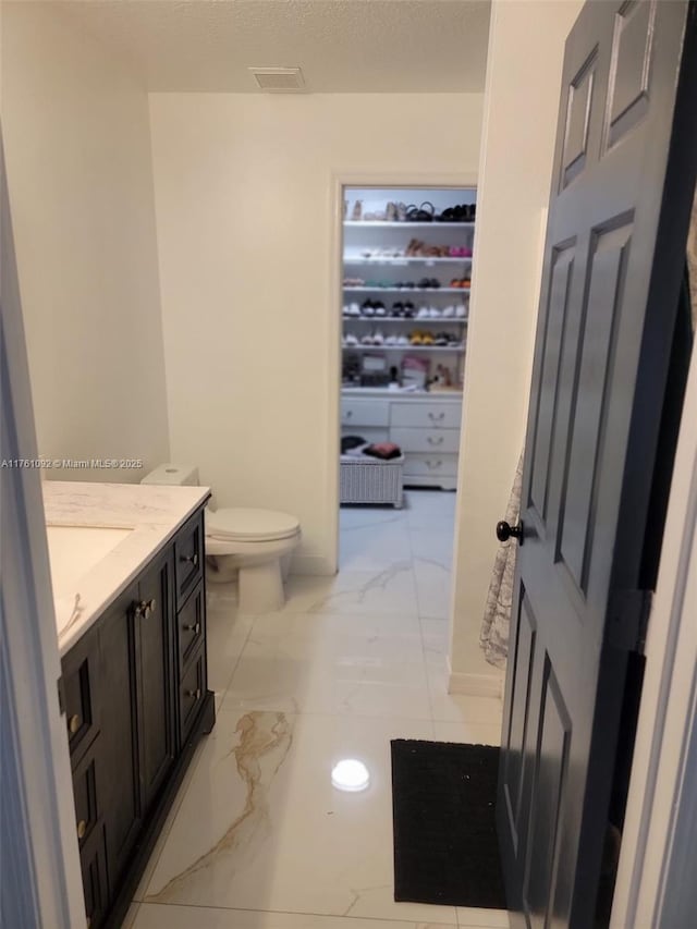 bathroom featuring vanity, visible vents, a textured ceiling, toilet, and marble finish floor