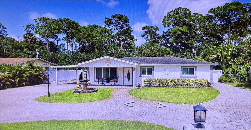 single story home featuring an attached carport, fence, a front yard, stucco siding, and driveway