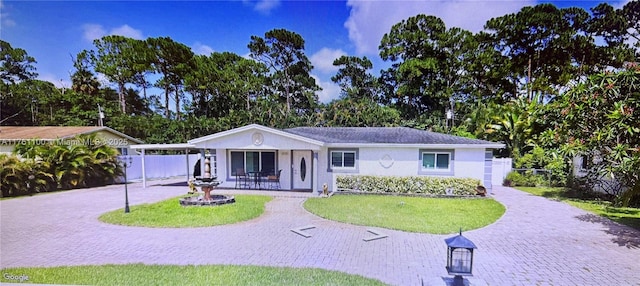 single story home featuring decorative driveway, an attached carport, a front lawn, and fence