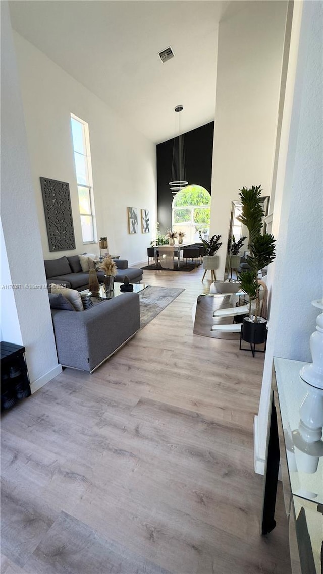 living room with a high ceiling, wood finished floors, and visible vents