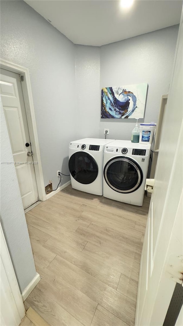 laundry room featuring laundry area, light wood-style floors, baseboards, and washing machine and clothes dryer